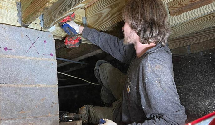 Person repairing crawl space with equipment