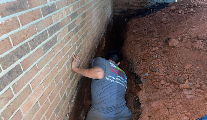 An expert is working on waterproofing a basement.