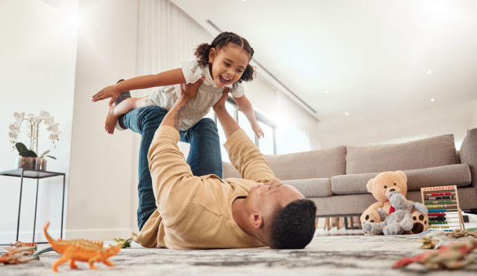 Father lying on the floor playing with his daughter in a cozy living room