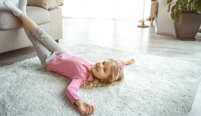 Smiling girl lying on a soft rug in a cozy living room